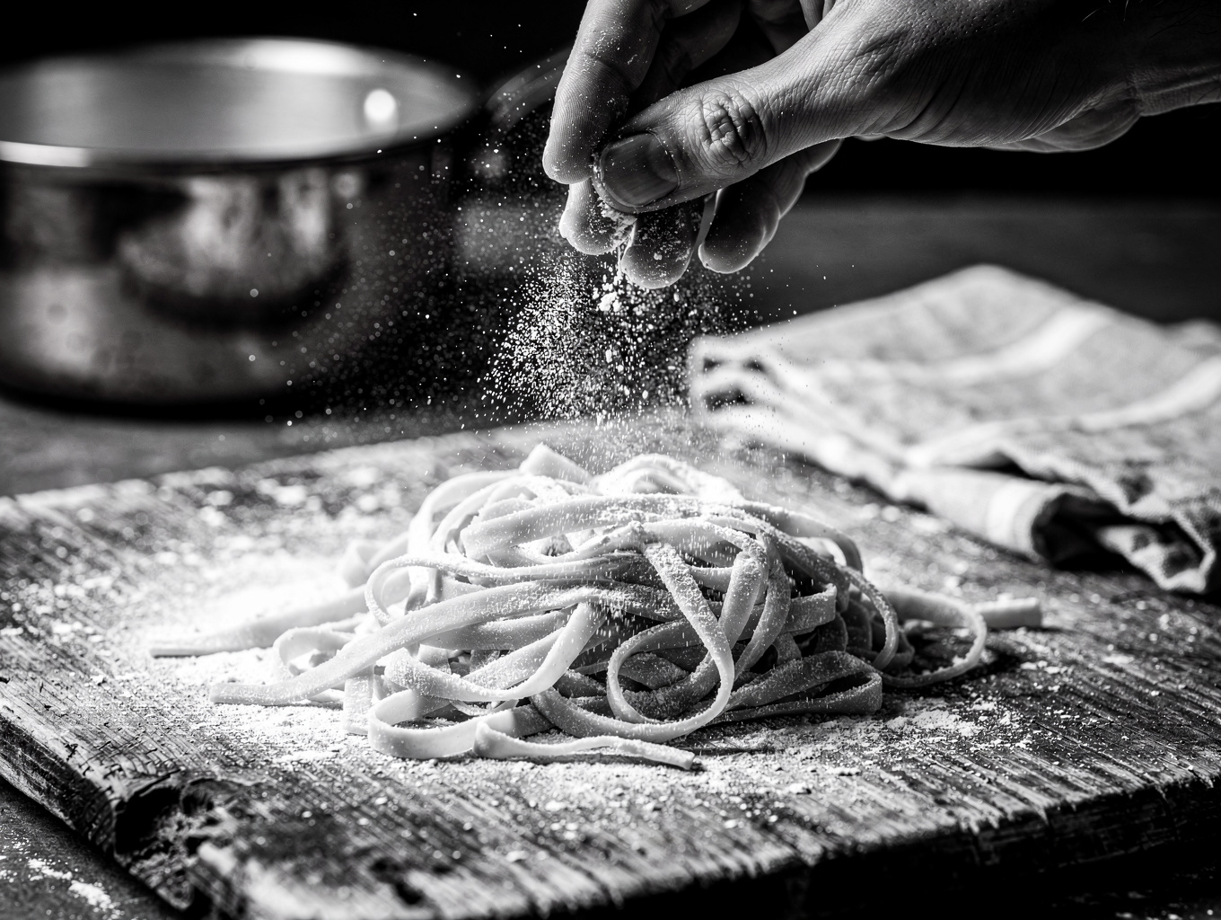 Chef hands dusting semolina flour over fresh pasta