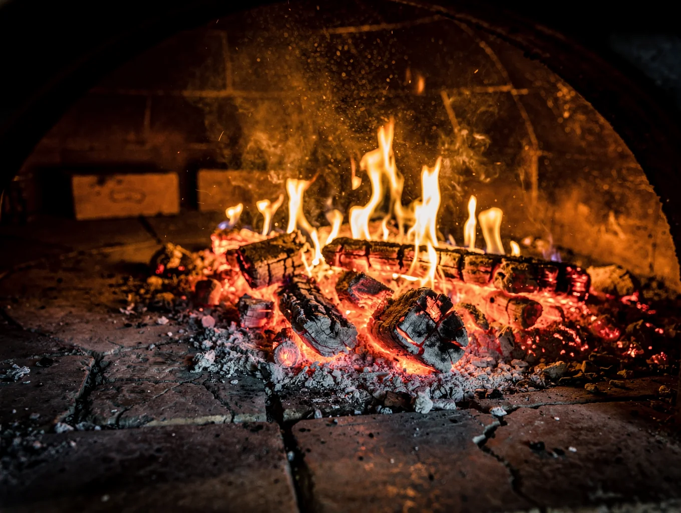 Glowing wood embers inside Italian cast iron hearth